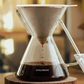 Coffee being brewed through a glass coffee maker with 'Ovalware' branding.