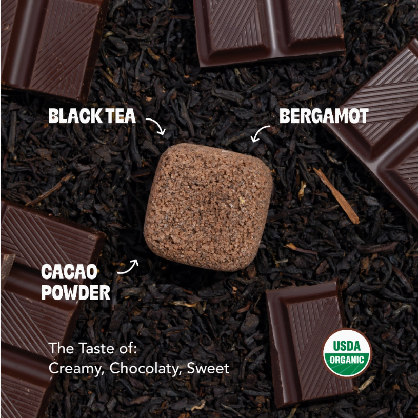 Chocolate earl grey tea drop surrounded by with tea leaves and chocolate with labeled ingredients on a dark background
