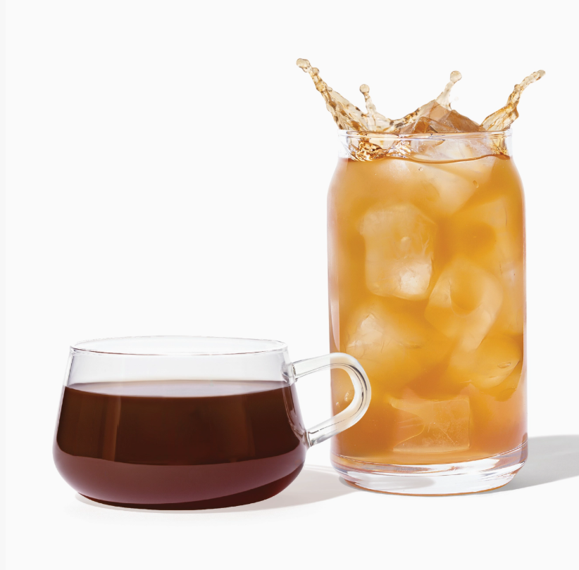 Glass of iced tea with a splash next to a cup of dark tea on a white background