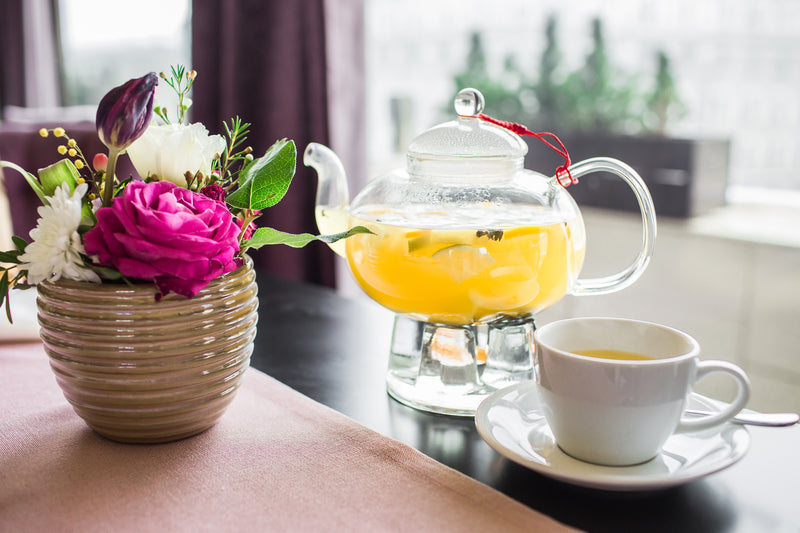 Pineapple Tea in Glass Tea Pot on Stand By White Cup and Flowers